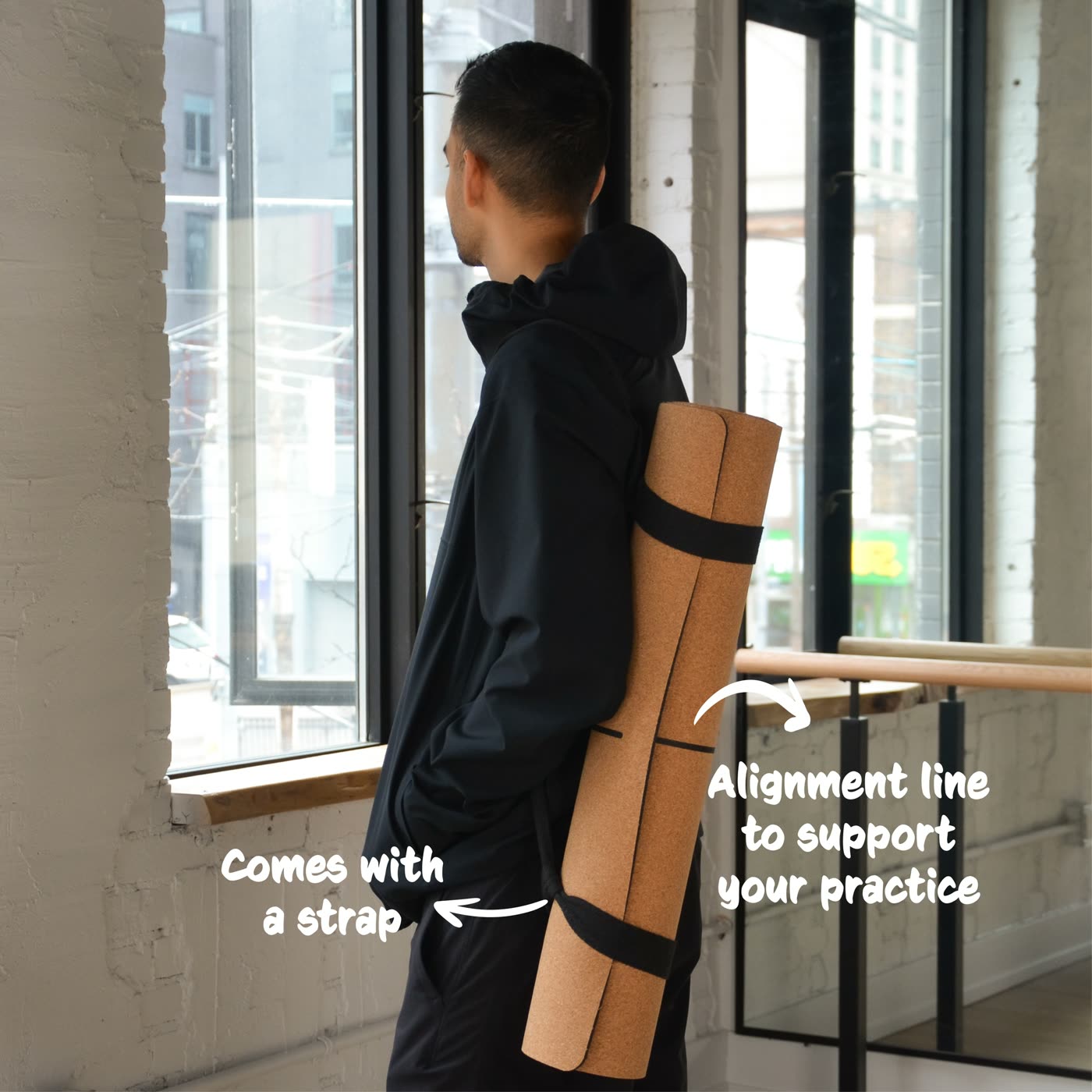 A cork yoga mat carried on its strap, labelled: comes with a strap, alignment line to support your practice.