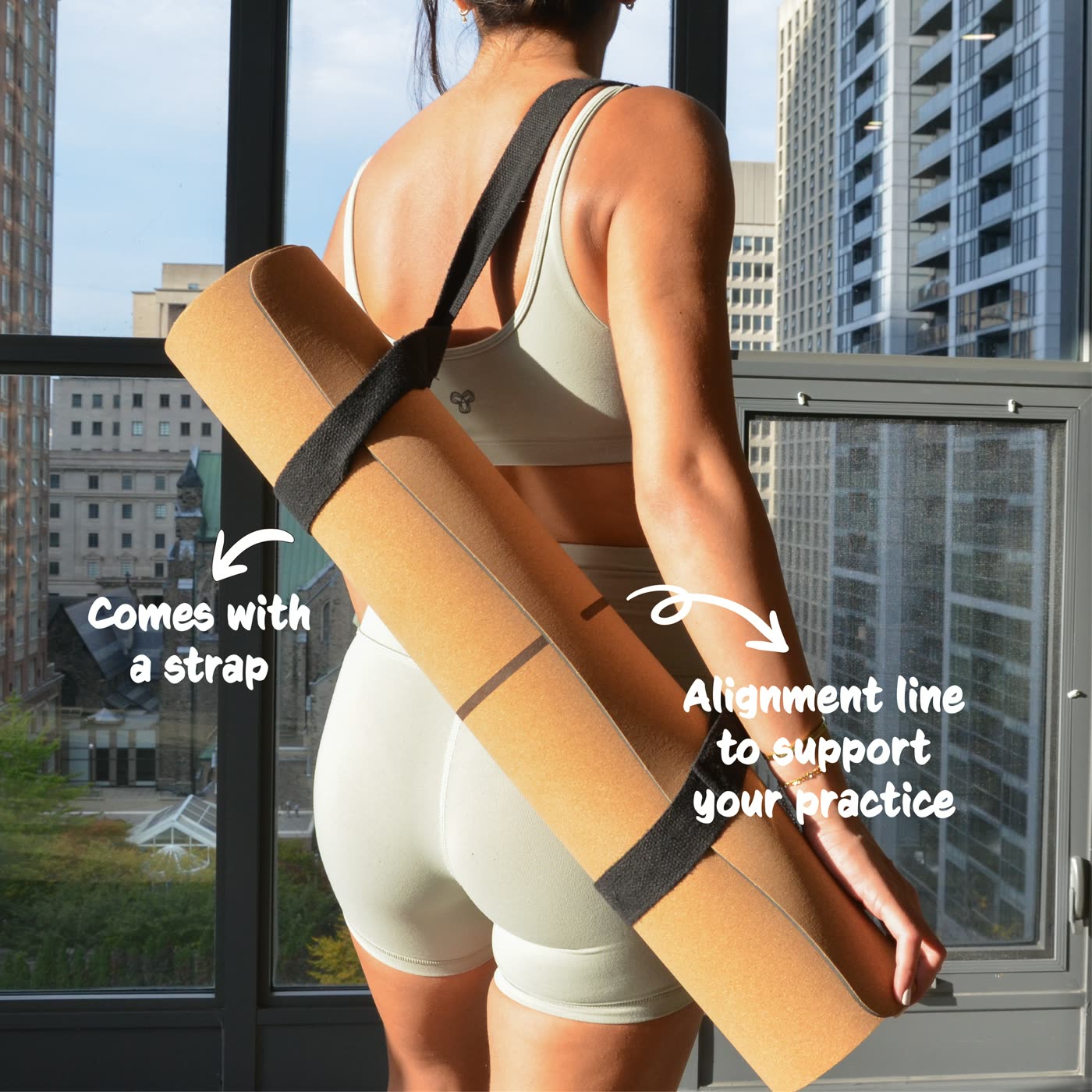 A cork yoga mat carried on its strap, labelled: comes with a strap, alignment line to support your practice.